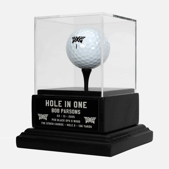 PXG black hole in one trophy that holds a pxg golf ball on a tee inside of the trophy box on a white background