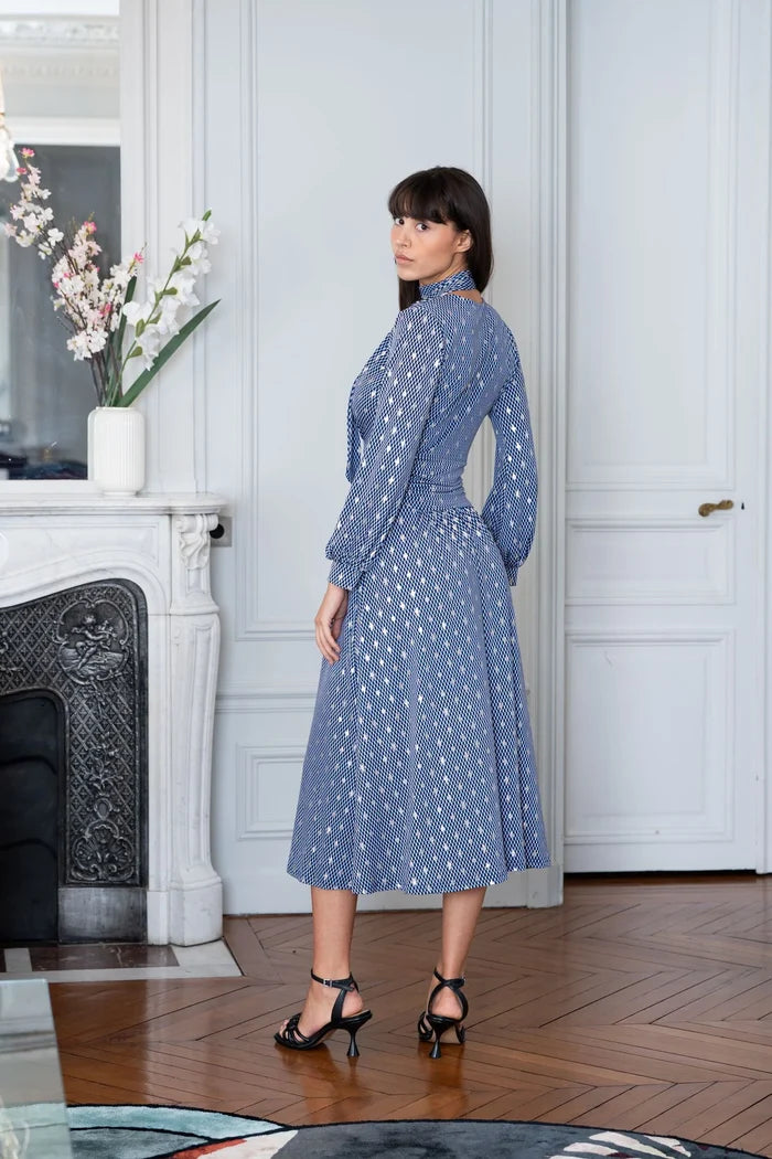 Woman poses in a blue geometric print dress in a Parisian apartment