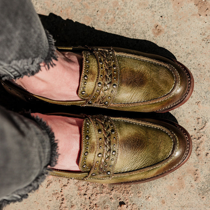 Olive green leather MYLA oxford loafers featuring a western silhouette, braided leather band, and silver stud details.