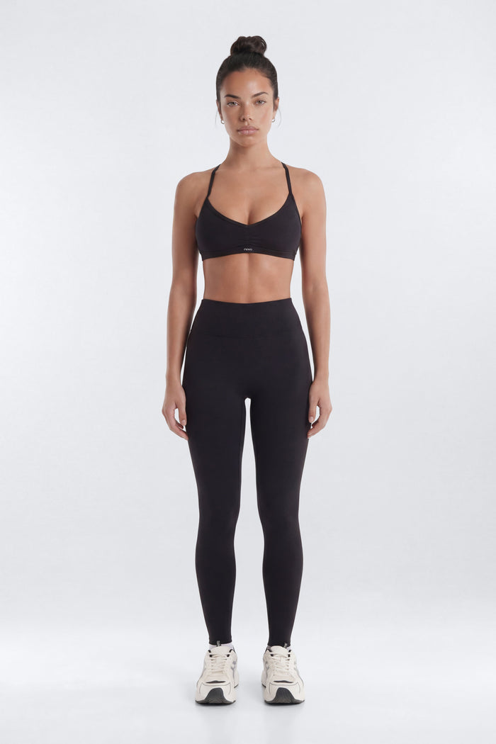Woman wearing a black sports bra and leggings on a white background