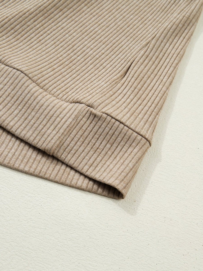 Close-up of a beige ribbed sweater sleeve on a light background