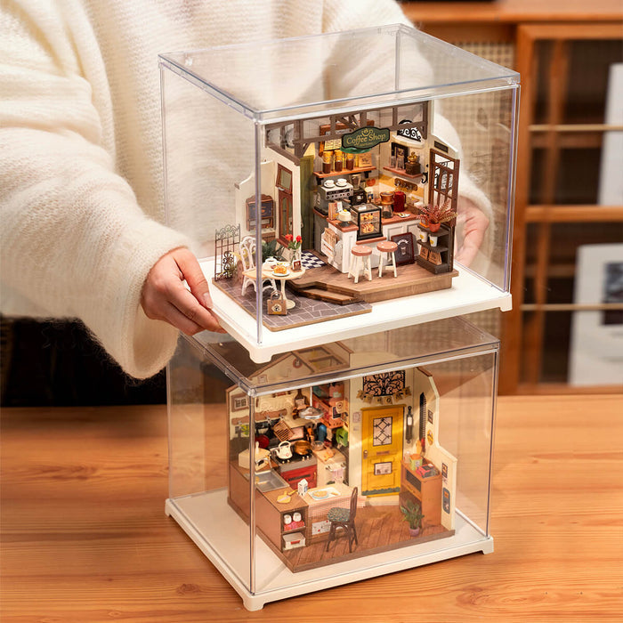 Two Rolife miniature dollhouses in stacked clear acrylic display cases being held by a person