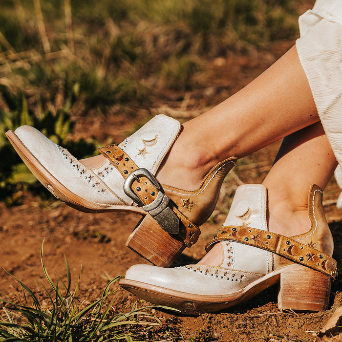 Beige STARDOM western booties with celestial star cutouts, metal studs, buckled strap, and stacked heels.