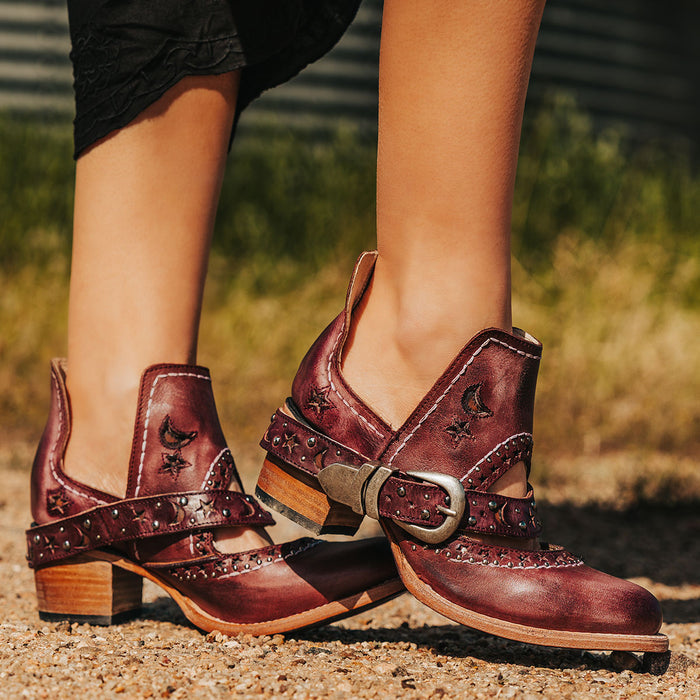 Wine STARDOM western booties with celestial star cutouts, metal studs, buckled strap, and stacked block heel.